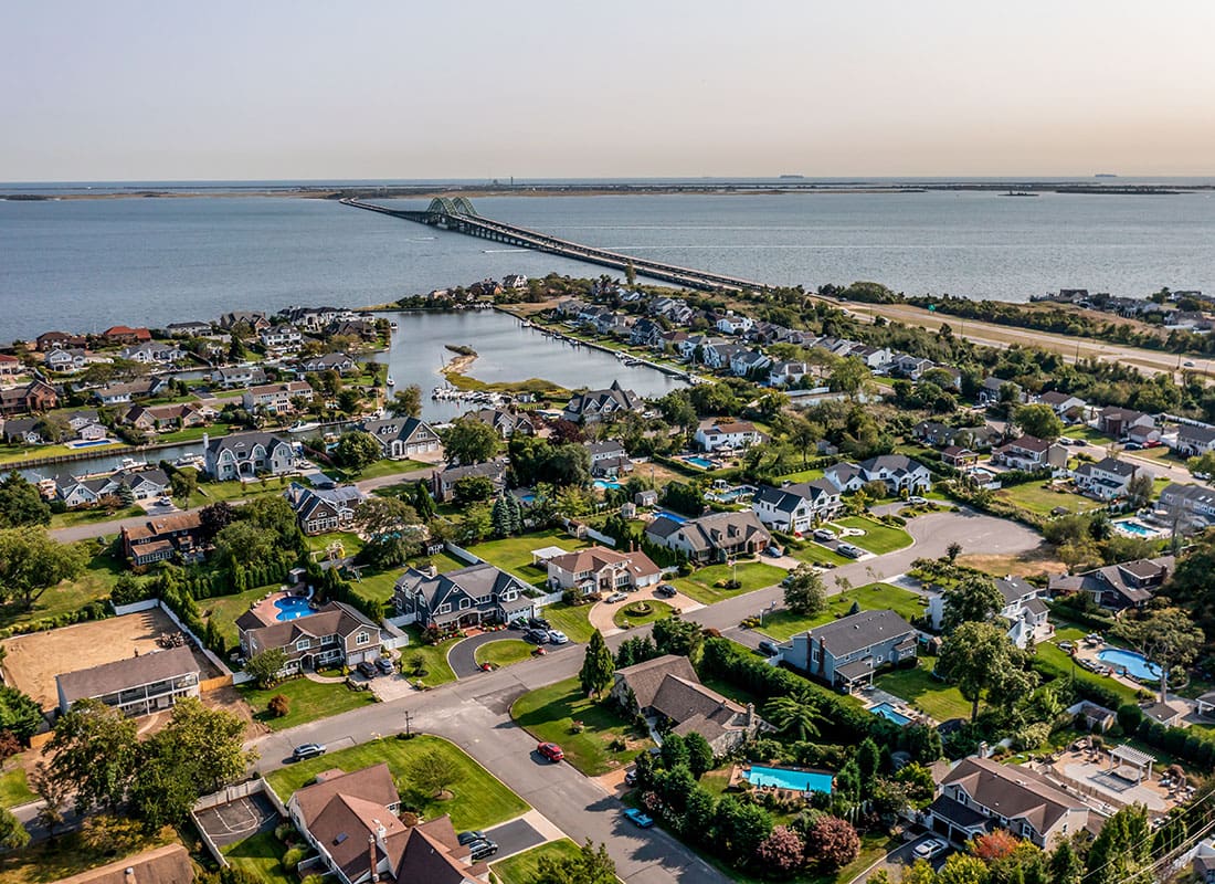 Plainview, NY - Aerial View of Homes by the Water Surrounded by Green Foliage on a Sunny Day in Plainview New York